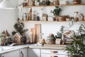 Ceramiczny domek w kształcie piernikowej chatki ze śnieżnym wiankiem i otworami, przez które wydobywa się światło świeczki.