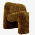 Designerski fotel boucle Madam Stoltz w kolorze musztardowym z miękką tapicerką i rzeźbiarską bryłą.