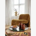 Designerski fotel boucle Madam Stoltz w kolorze musztardowym z miękką tapicerką i rzeźbiarską bryłą.